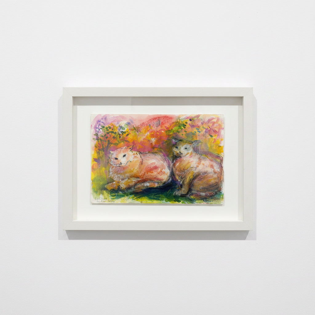 Framed painting of two cats in a colorful landscape on a white wall