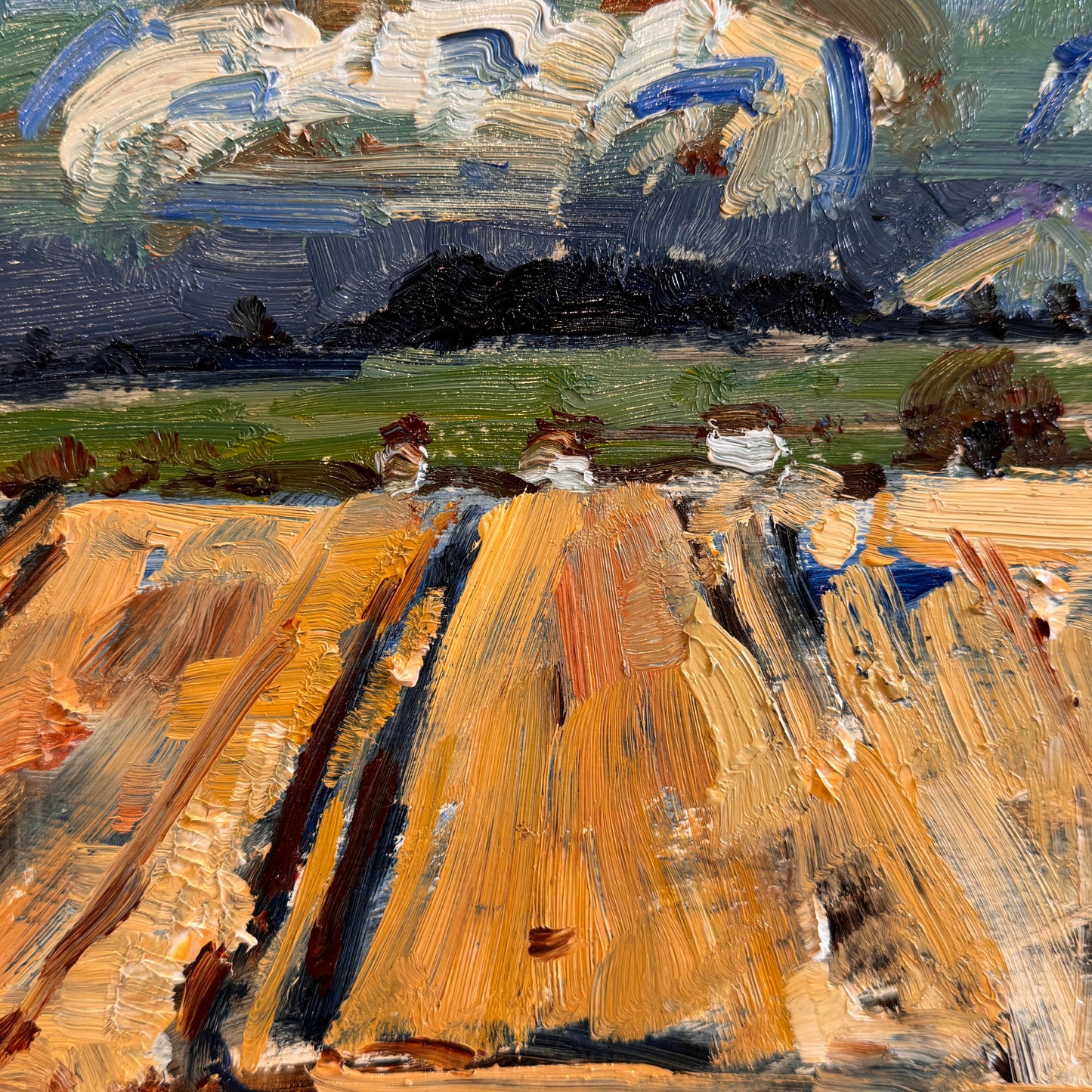 An oil painting of a harvested field with reaped crops under a dramatic cloudy sky, presented in a white frame.