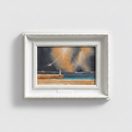 a painting of a lighthouse in St Ives Bay, with a stormy sky overhead. In a white ornate frame.