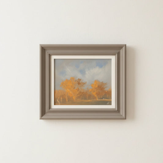 Framed painting of a landscape with trees and sky on a white wall