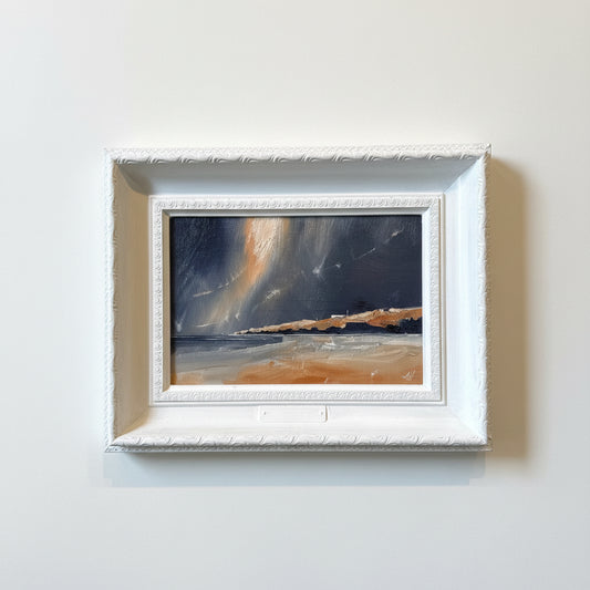 a painting of a stormy beach scene. in a white painted ornate frame.