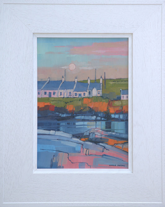 Framed artwork of a coastal scene with houses and a sunset.