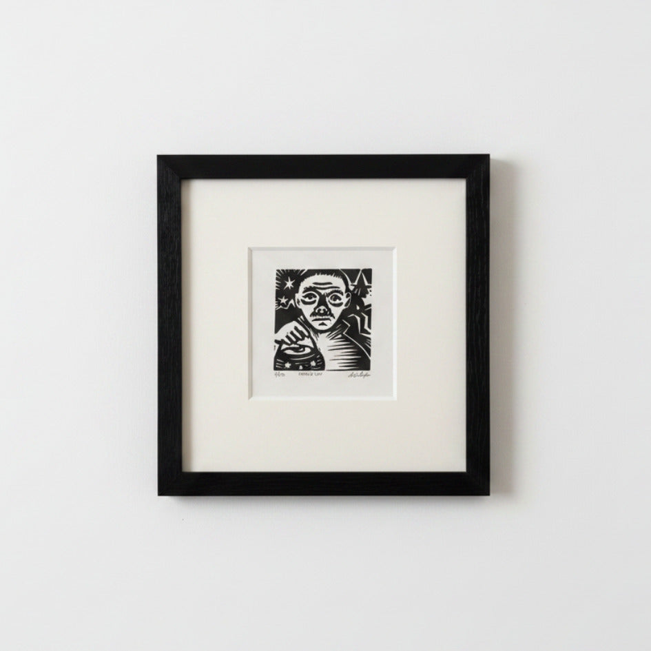 A framed black and white art print featuring a stylized portrait of a woman, mounted with a wide white mat inside a black frame against a light gray wall.