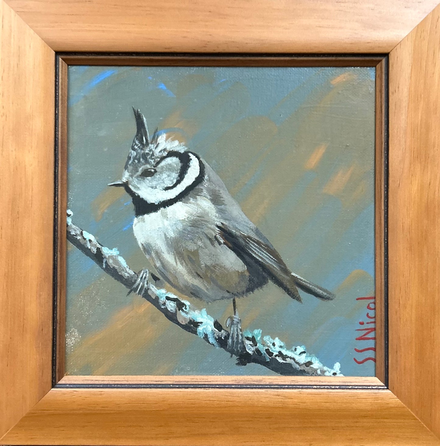 Painting of a bird perched on a branch with a wooden frame.