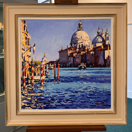 Framed painting of a cityscape with a dome and water reflections on an easel.