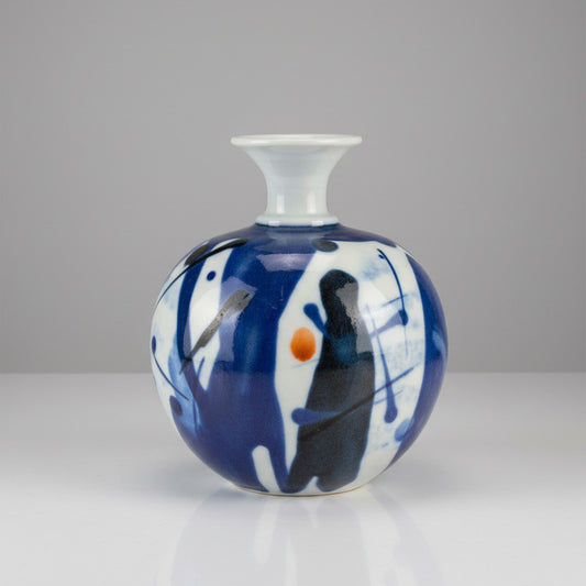 Decorative cermaic vase with blue, white, and black patterns on a textured white background