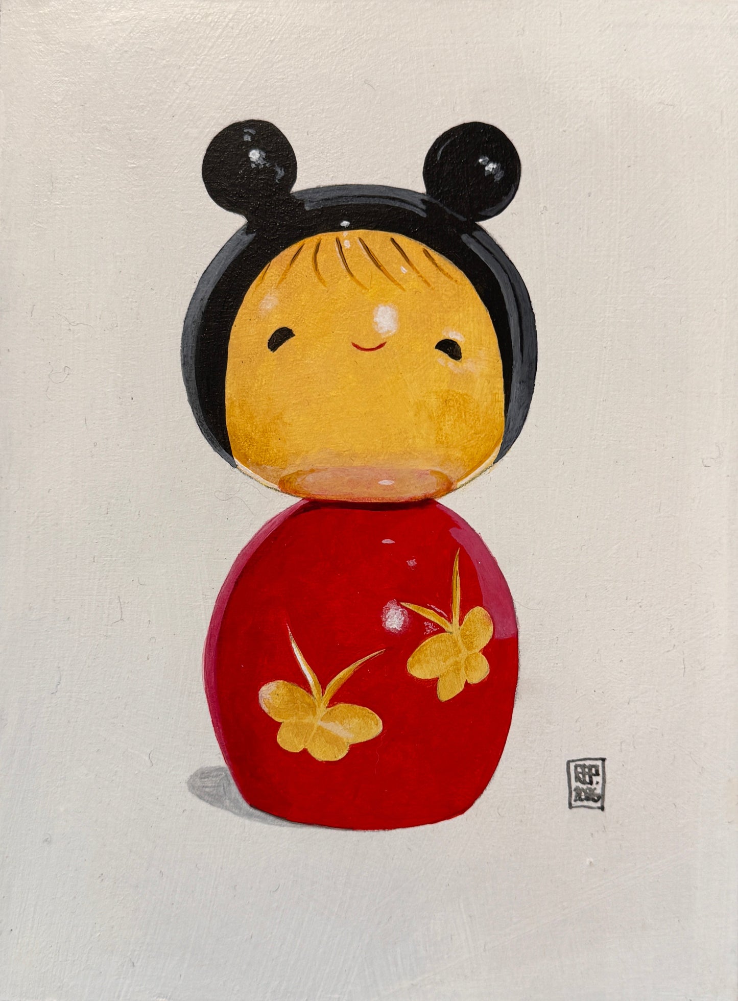Framed artwork of a stylized face with black, yellow, and red elements on a textured wall.