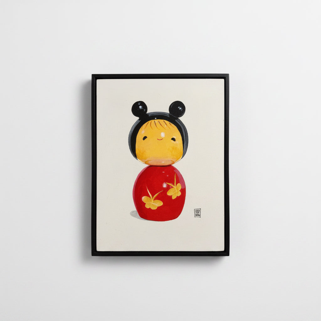 Framed artwork of a traditional Japanese kokeshi doll with black hair and red body on a white background