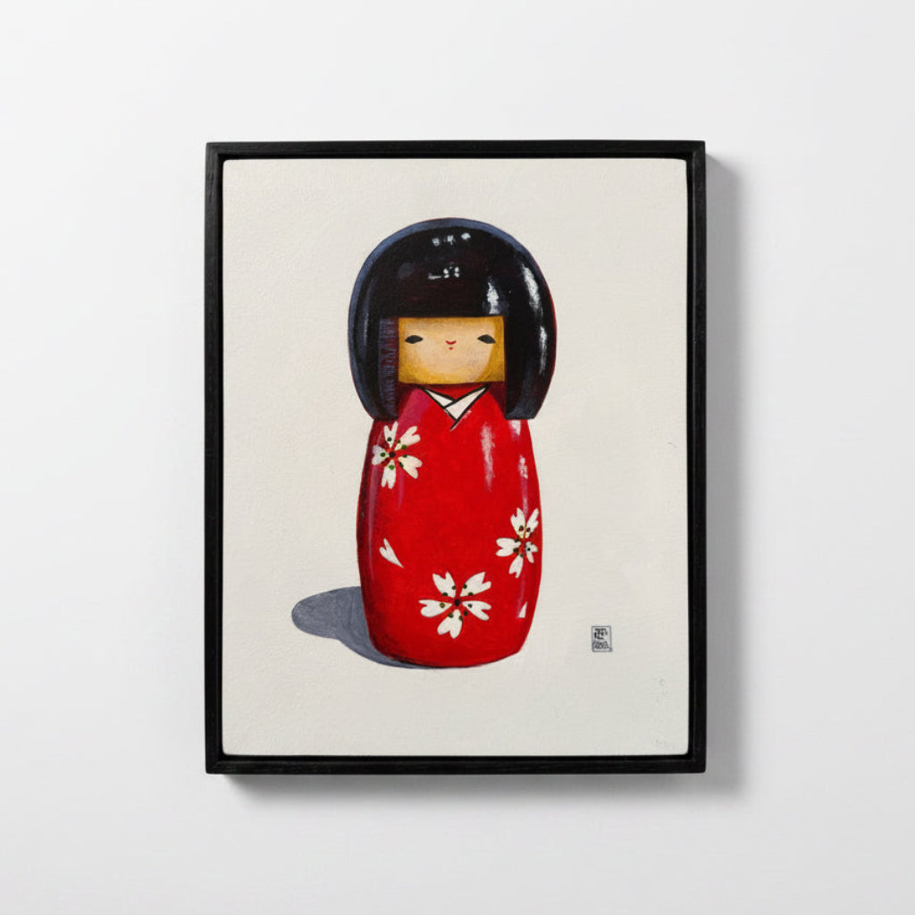 Framed artwork of a red kokeshi doll on a white background