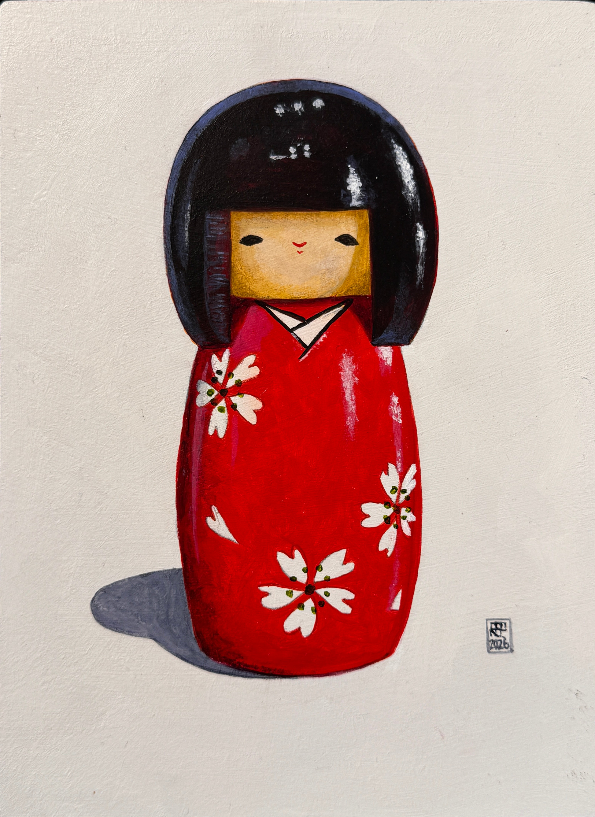 Red Japanese kokeshi doll with black hair and white floral patterns on a beige background