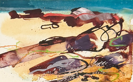Abstract watercolor painting depicting a beach scene with dark seaweed or kelp on a sandy shore under a blue sky.