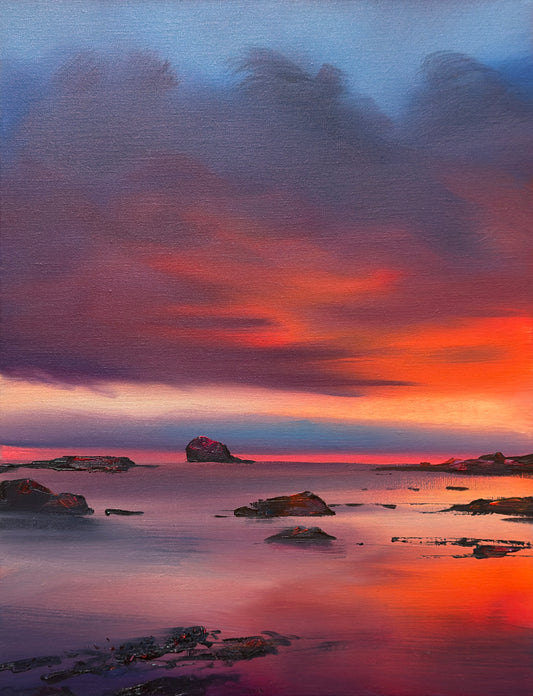 A colorful coastal landscape painting featuring a dramatic sunset sky with deep blue, purple, and bright orange clouds, reflected in calm water with dark rocky islands.