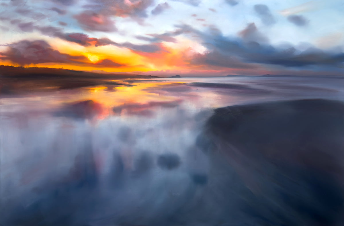 A long-exposure landscape photograph of a sunset over a calm body of water, with dramatic orange, yellow, and blue clouds reflected in the misty surface.