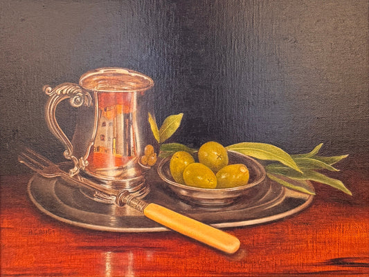 Framed still life painting with a glass pitcher and fruit on a table.