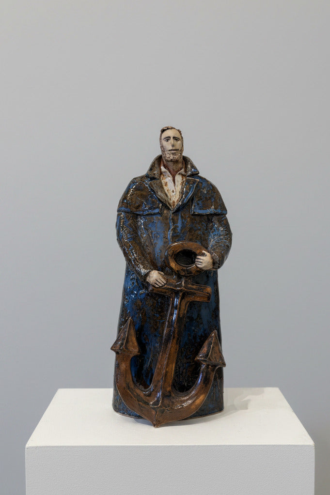 Statue of a person holding an anchor against a white wall