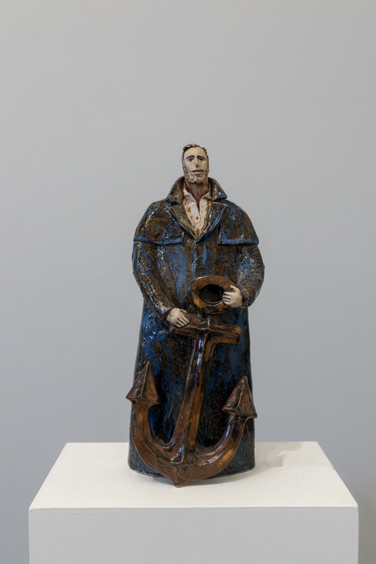 Statue of a person holding an anchor against a white wall