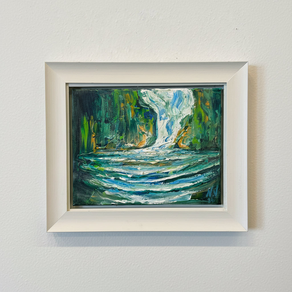 Framed abstract painting with green and blue tones on a white wall.