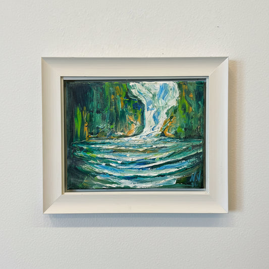 Framed abstract painting with green and blue tones on a white wall.