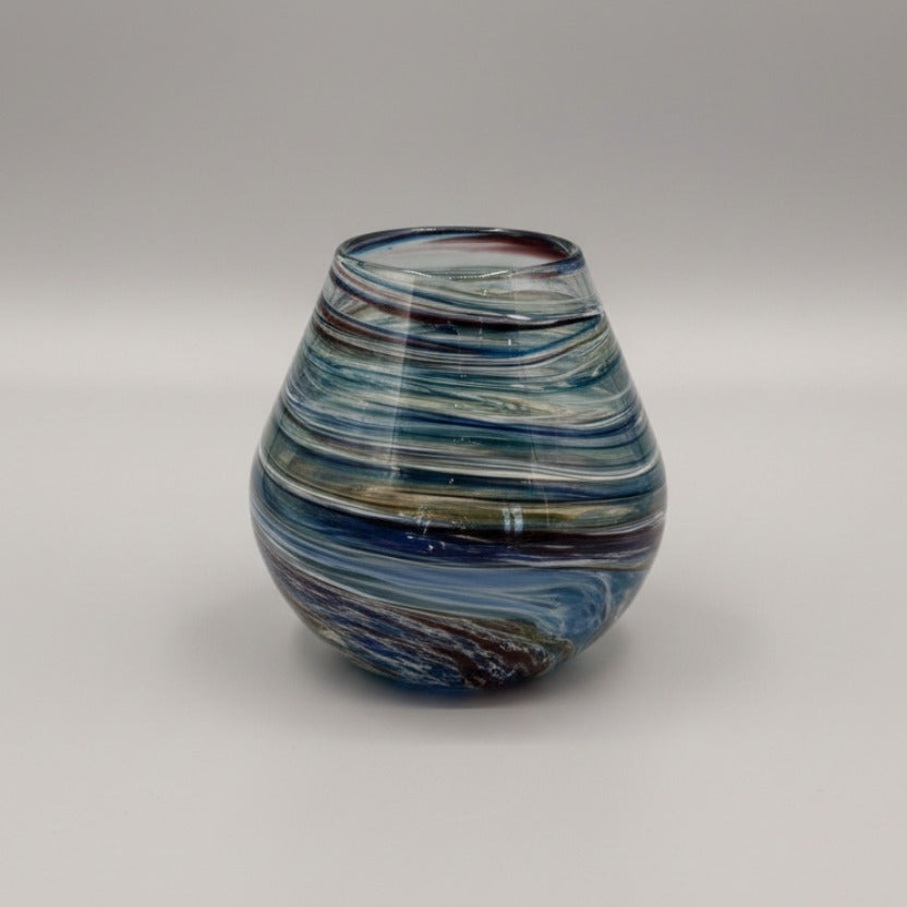 Multicolored glass vase on a textured white surface