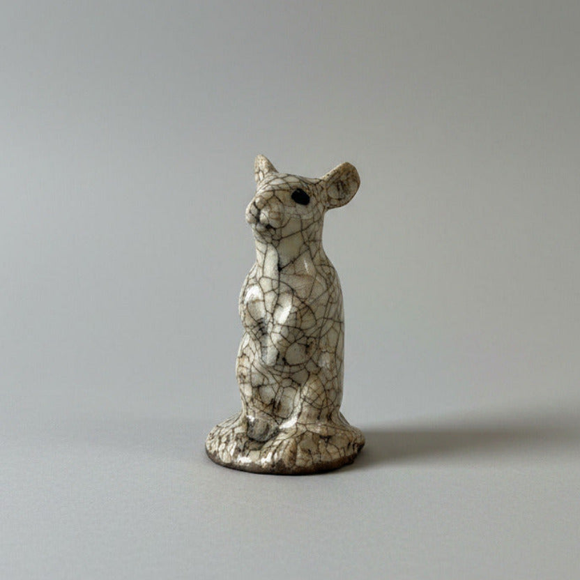 Decorative ceramic mouse figure on a textured white wall