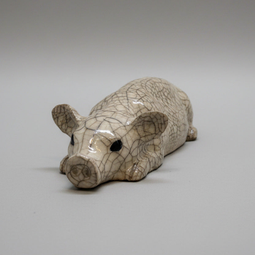 Small ceramic pig figurine on a textured white wall