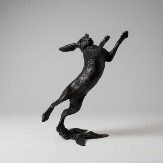 Black hare figurine on a white surface with a light gray background