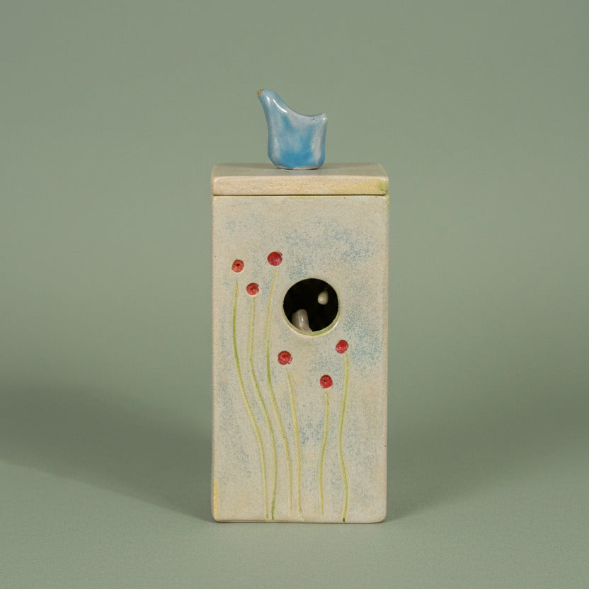 ceramid decorative item with a blue bird on the top of the lid, and a nest of birds inside.