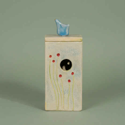 ceramid decorative item with a blue bird on the top of the lid, and a nest of birds inside.