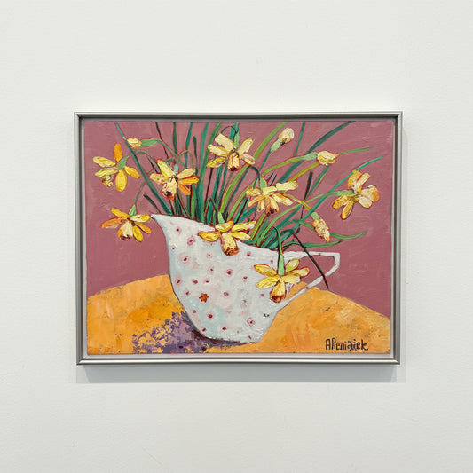 Framed artwork with flowers and a ladybird on a yellow table against a pink wall