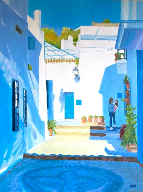 Colorful street scene with blue buildings and a pool in a Mediterranean-style town.