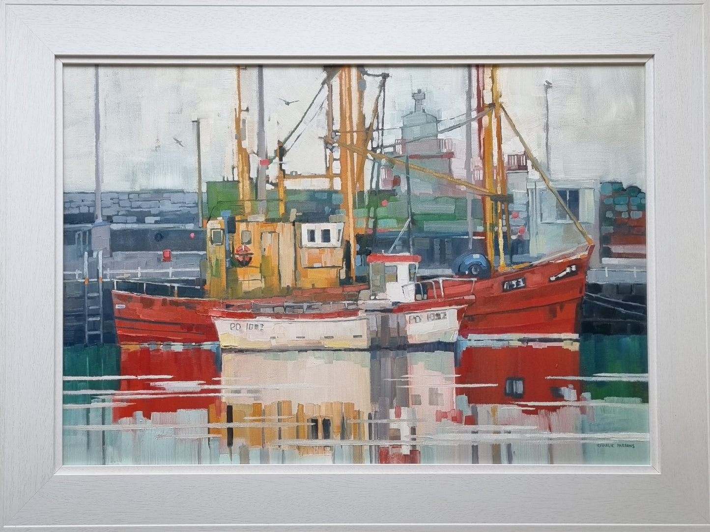 Framed artwork of a harbour scene with boats and industrial elements.