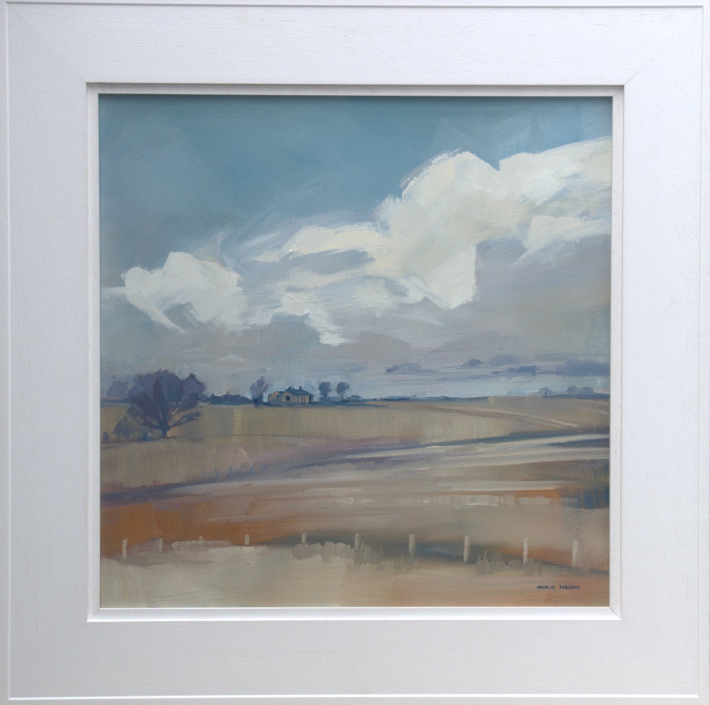 Framed painting of a landscape with fields and clouds