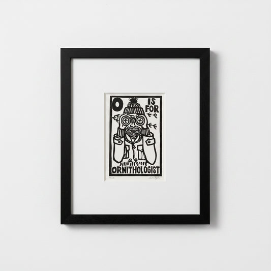 A framed black and white art print featuring a whimsical illustration of a bird wearing binoculars and the text 'O IS FOR ORNITHOLOGIST', displayed in a black frame against a light gray wall.