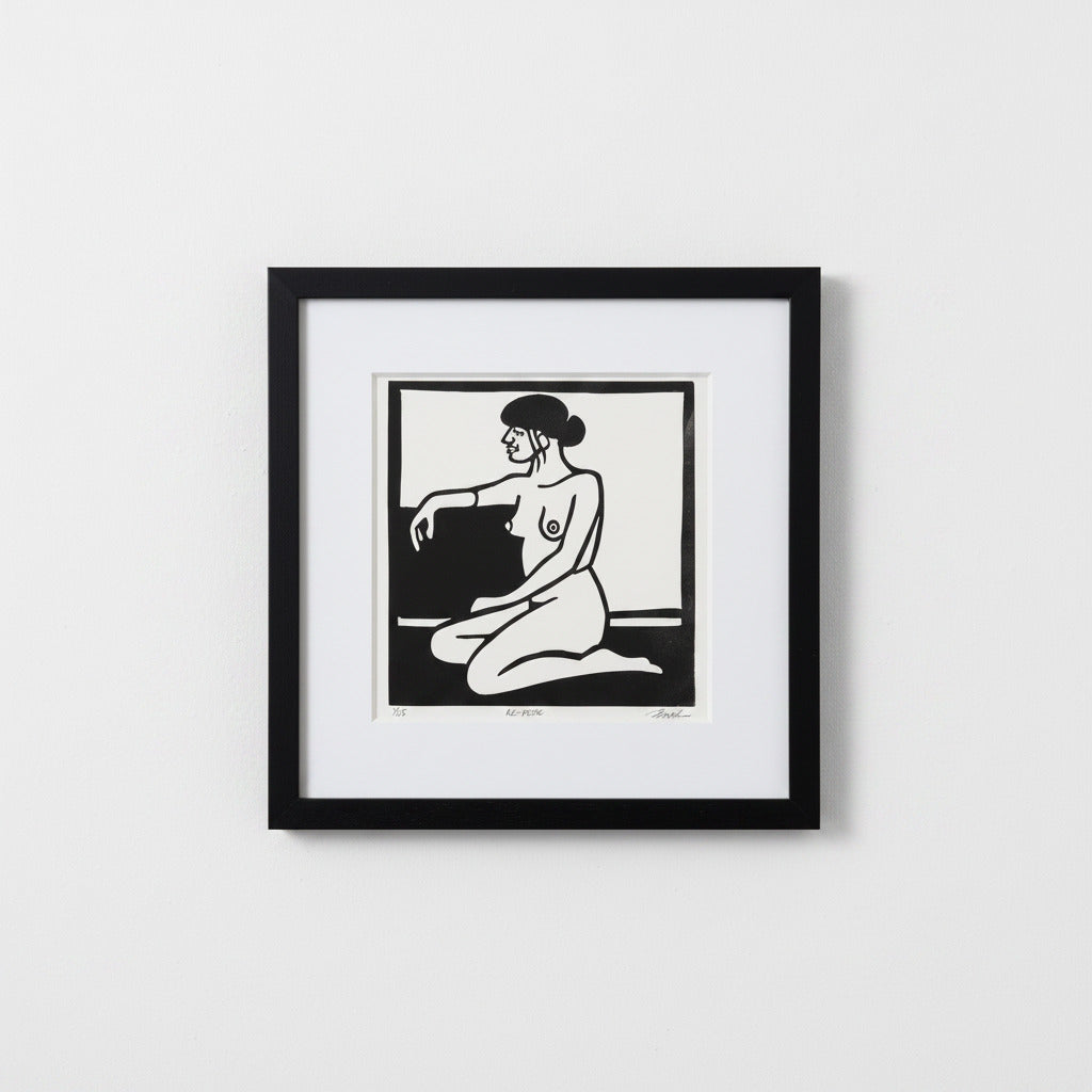 A framed black and white art print featuring a minimalist illustration of a kneeling nude woman, presented in a black frame with a white mat against a light gray wall.
