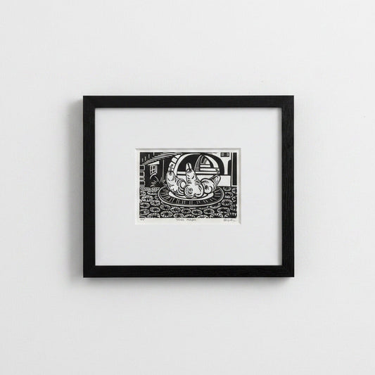 A framed black and white art print featuring a whimsical illustration of a rabbit on a plate, displayed on a clean white wall.
