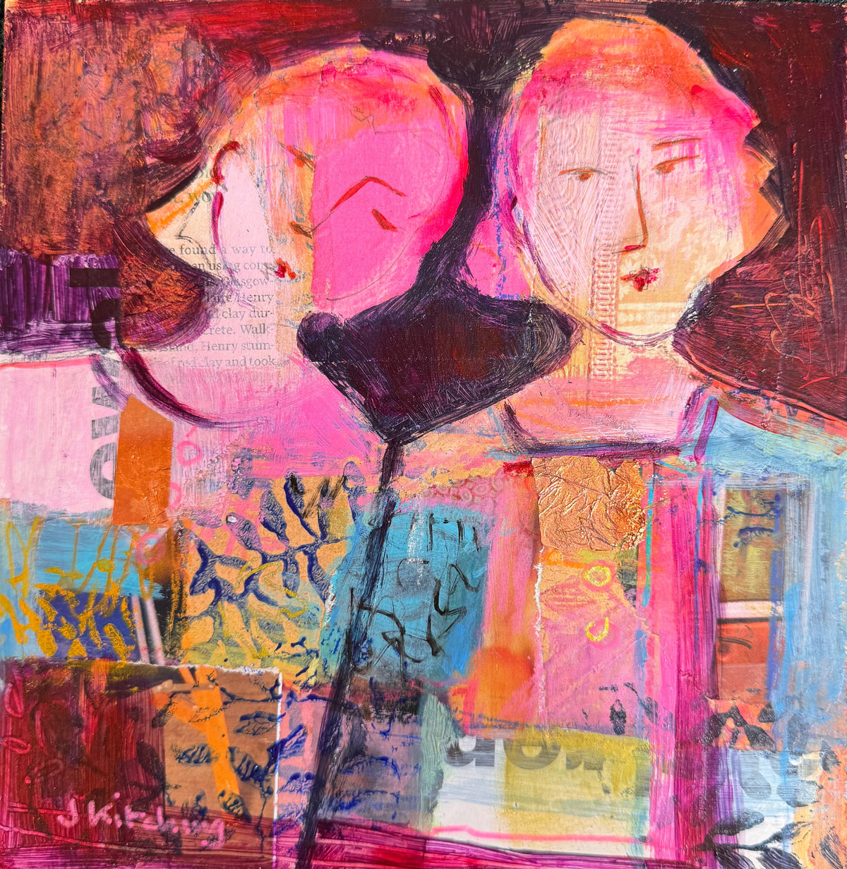An abstract mixed-media painting on canvas featuring two stylized faces in pink and orange tones, layered with geometric blocks, brushstrokes, and collage elements in pink, blue, yellow, brown, and black, displayed on a green grass-like surface.