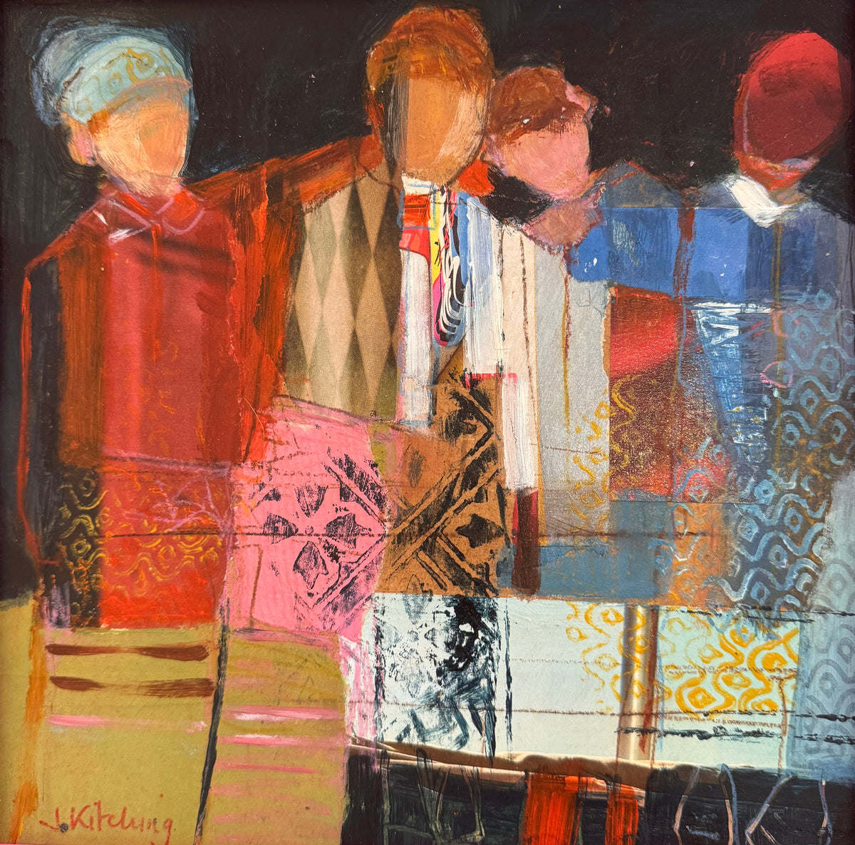 A framed abstract painting featuring four stylized figures in warm and cool tones, enclosed in a bright pink frame. The artwork is photographed resting on a desk with papers visible around it.