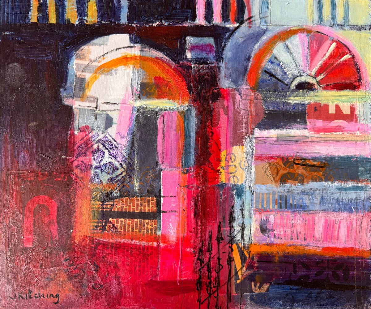 An abstract mixed-media painting on a square canvas, featuring bold brushstrokes of red, pink, orange, black, white, and blue, placed on a green textured carpet.