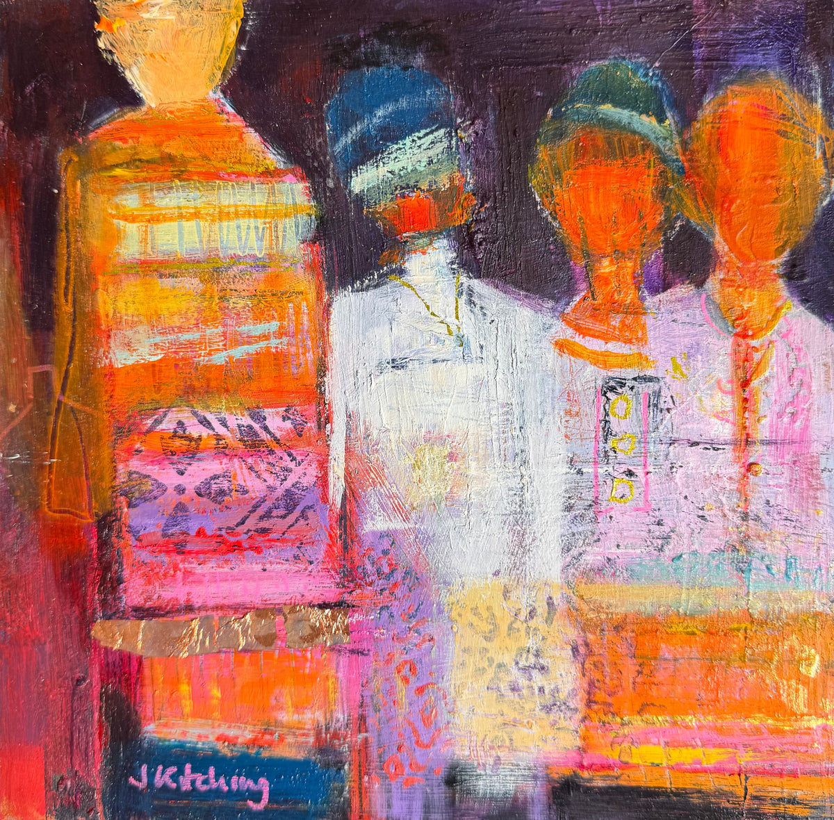 An abstract painting of three stylized human figures in warm and cool colors, displayed on a textured green grass-like surface. The painting features expressive brushstrokes in orange, yellow, pink, purple, blue, and white, with a visible artist signature in the lower left corner.