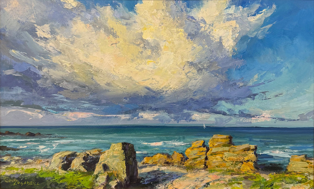 A framed coastal landscape painting featuring dramatic blue and white clouds over a rocky shoreline and ocean, displayed in a black frame on a wooden easel.