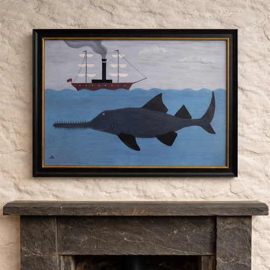 Framed artwork of a sawfish and ship on a blue background, displayed above a fireplace.