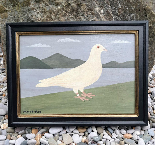 Framed artwork of a white pigeon on a landscape with mountains and water.