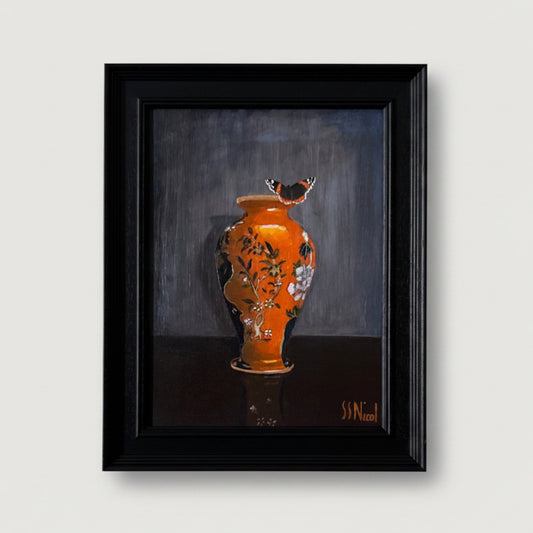 Framed artwork of an orange vase with floral patterns and a butterfly on a dark background.