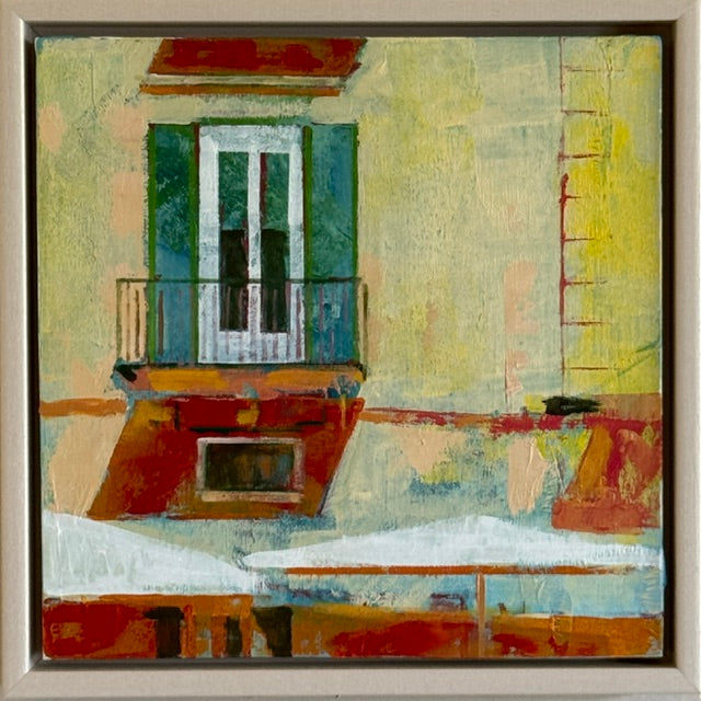 An abstract painting of a building facade with a balcony and shutter, rendered in textured brushstrokes of yellow, green, red, orange, and white, enclosed in a light wood frame.