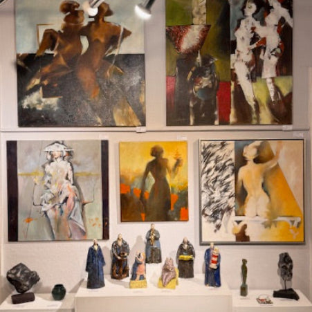 Collection of framed artworks and sculptures displayed in a cabinet.