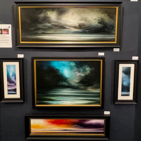 Wall with framed artworks depicting celestial scenes on a dark background