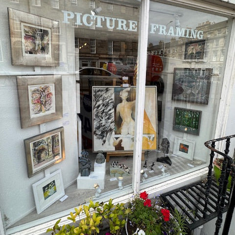 Gallery window display with framed pictures and a sign for 'Picture Framing'.